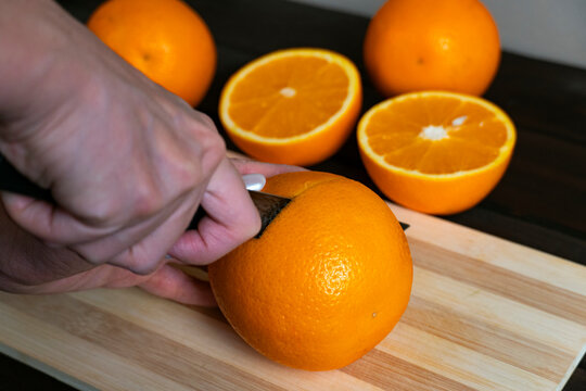 Man cutting fresh oranges on wooden board