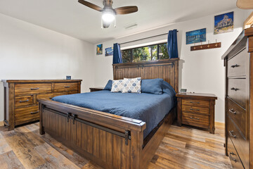 A decorated bedroom with a bed, dresser, nightstand, and fan