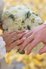 Wedding bouquet with wedding rings and hands of the newlyweds.
