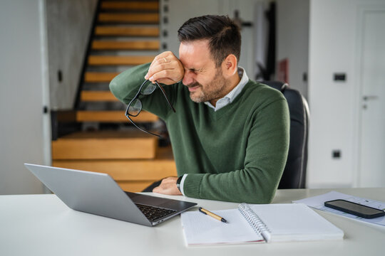 Man experiencing eye strain headache from working on laptop