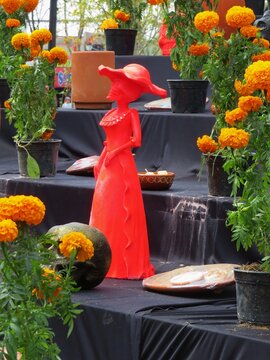 traditional red clay skeleton statue in a altar -ofrenda of the day of the dead in Mexico with marigold-cempasuchil