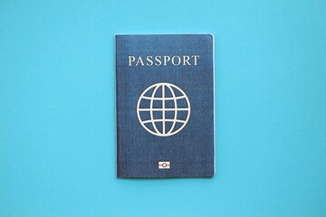 Generic passport book on light blue paper background close up. Travel document on blue surface