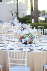 Wedding table decoration with fresh blue and pink flowers, plates and candles