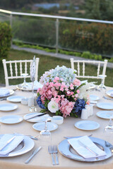 Wedding table decoration with fresh blue and pink flowers, plates and candles