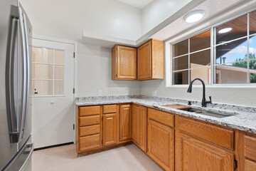 A kitchen with wooden cabinets, granite countertops, and a sink