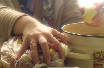 A close-up, expressive shot showing a person's hands carefully holding a piece of a yellow apple, with the palm holding something