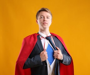 Businessman wearing superhero costume on yellow background