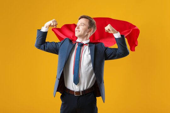 Businessman wearing superhero cape on yellow background