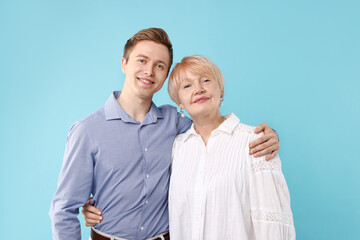 Fototapeta premium Mother and son hugging on light blue background