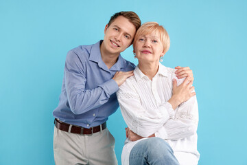 Son hugging his mother on light blue background