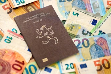 Luxembourg passport lies on big amount of euro money banknotes close up. Rich life and travel in Europe concept