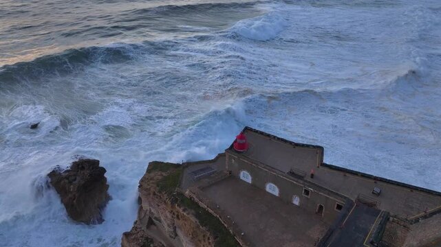 Lighthouse of Nazare, Farol da Nazare. The world's biggest waves in Portugal, Aerial Drone Shot During Sunset Time.