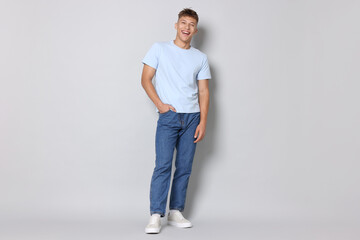 Fototapeta premium Handsome young man in stylish jeans on light grey background