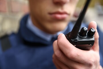 Police officer with radio on city street, closeup © New Africa