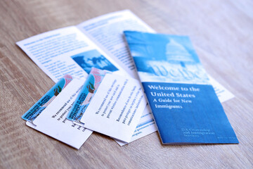 Permanent resident green card in envelope and guide for new immigrants lies on wooden table close up