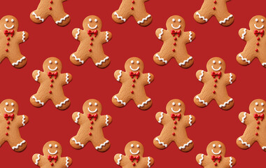 Obraz premium Seamless pattern of smiling gingerbread men with red bows on a light red background. Festive wallpaper ideal for Christmas backgrounds, wrapping paper, and holiday themes.