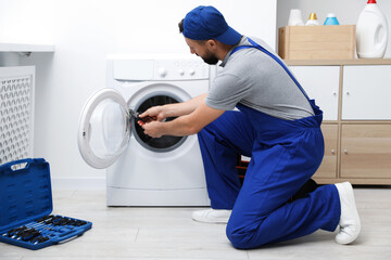 Professional repairman fixing broken washing machine indoors