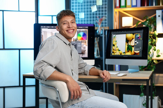 Professional retoucher editing photo on computer at table in office