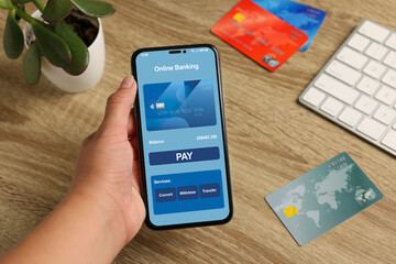 Woman using smartphone for online payment, closeup. Credit cards and computer keyboard on table