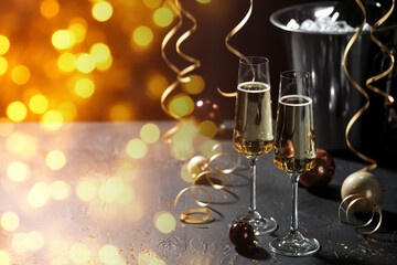 Sparkling wine in glasses and festive decor, bokeh lights. New Year greeting card