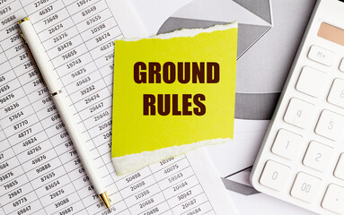 Fototapeta premium Yellow torn paper with text ground rules on office documents with pen and calculator