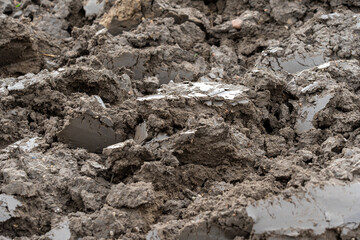 An abstract close-up of freshly plowed dark brown earth showing rough, uneven clumps and chunks of soil. The image highlights the texture of farmland and agriculture