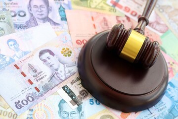 Thai baht currency money bills and wooden judge mallet close up. The concept of judgment or auction