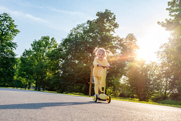 Girl on scooter. Riding child outdoor fun. Sunshine road freedom lifestyle.