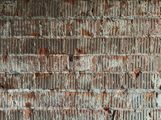 Moss-covered red brick wall with rust stains, cracks, and lichen growth, showcasing weathered rustic texture and natural urban patina