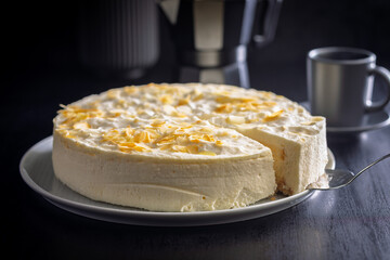 Sweet creamy cake on plate on black table.