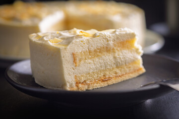 Sweet creamy cake on plate on black table.