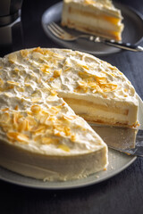 Sweet creamy cake on plate on black table.