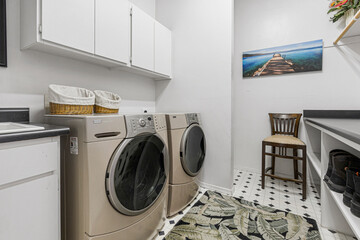 An interior laundry room that includes a washer, dryer, and a chair