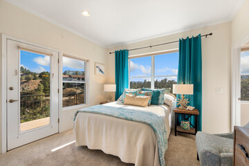 A cozy bedroom with a comfy bed, bright windows, a chair, and dresser