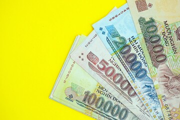 Vietnamese dong money bills in big amount close up on yellow. Finance and banking concept