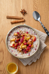 Overnight oatmeal with apple, cranberry and cinnamon in a plate on a wooden background with honey