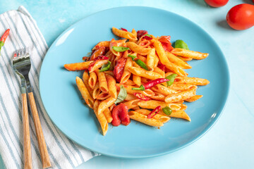 Classic penne all'Arrabbiata with tomato and chilli sauce on blue background