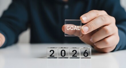 Hand holding transparent cube with word goal above 2026 number blocks, concept of new year planning and business success target