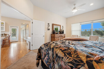 A spacious bedroom with a large bed and ceiling fan for cooling