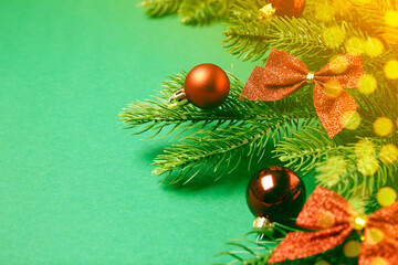 Christmas balls, fit tree branches, bows and bokeh lights on green background. Greeting card design