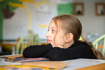 A girl is sitting at a desk with her head down