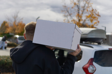 Delivery man holding cardboard boxes beside a parked minivan, representing courier work, package shipping, and efficient logistics service.