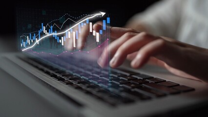 A focused view of hands typing on a laptop with an overlay of stock market data visualization, illustrating an upward trend in a tech-driven financial analysis concept. Copula