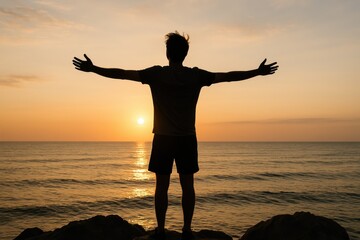 Young man with arms wide open by the sea at sunrise feeling free on rocky shore