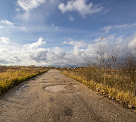 Road with a lot of potholes and a cloudy sky
