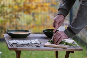 Cutting fresh herbs on wooden table outdoors