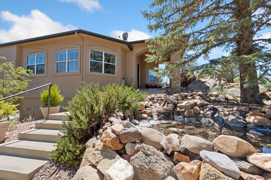A house with stairs is surrounded by rocks and trees