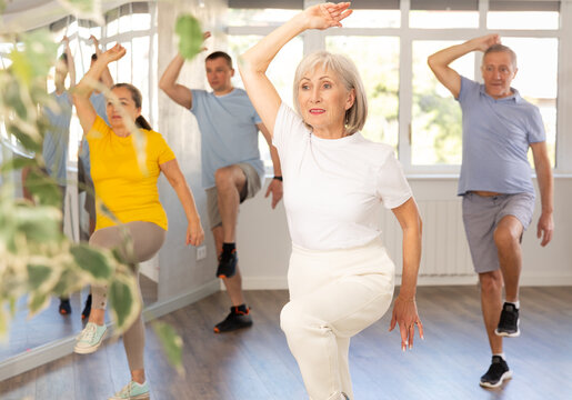 Cheerful elderly woman attending group choreography class, learning modern dynamic dances. Concept of active lifestyle of older generation..