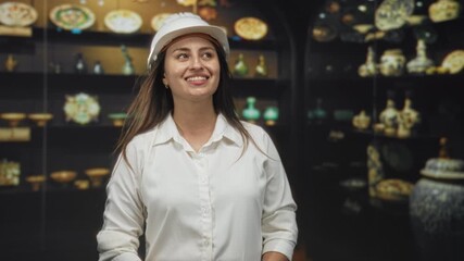Woman architect wearing a hardhat, smiling and looking up at a museum exhibit in a historic building; curiosity heritage preservation. - Powered by Adobe