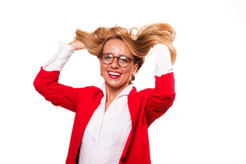 Businesswoman joyfully playing with her hair in a bright red jacket while smiling against a clean...
